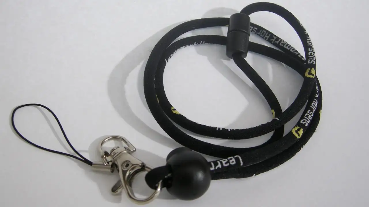 Rundvävd nyckelsnodd med vävd logga vars utformning påminner om ett skosnöre.